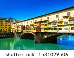 Ponte Vecchio or Old Bridge over the Arno River in Florence, Italy. Arch bridge with jewelery and art shops and colorful buildings is a famous tourist attraction