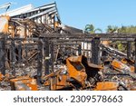 Small photo of New Port Richey, Florida USA - May 26, 2023: illustrative editorial image showing the charred wooden beams of townhomes and mangled metal left behind after a brush fire swept through