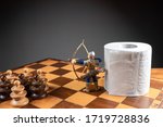 Small photo of Archer defending a roll of toilet paper from an army of pawns on a chessboard. Conceptual image representing egoism and avarice during coronavirus or 2019-ncov crisis