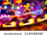Unfocused lights of a Merry-go-round or carousel with colorful blue, red, yellow, pink and orange illumination. Blurred lights traces and spots taken with Long Time Exposure on a fun fair in Germany. 