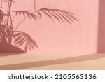 Premium podium with a shadow of tropical palm leaves on a pink and beige background. Minimal abstract background for the presentation of a cosmetic product. Showcase, display case.