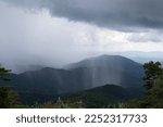 Small photo of Sheets of rain falling thickly on a mountain vista obscuring parts of the distance, rainy weather event from a cloudburst, horizontal aspect