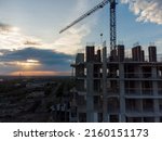 Small photo of Construction site with cranes against the background of the evening sky. Turret slewing cranes working at sundown at evening time, buildings under construction