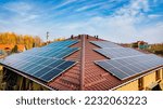 Small photo of Close up of solar panels on roof home. The panels have the same beautiful blue color as the sky. from the attic level you can view the street with trees on the ground.