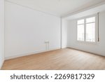 Small photo of View of an empty white bright room with window without furniture after painting and renovation with wooden floor and baseboards. Concept of beautiful laconic interior for various inspiring ideas