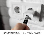Small photo of Unplugging USB cable from power adapter. Disconnect USB cord from the cellphone charger. Man hold USB plug against wall charger. Plug-in connector into european wall outlet or socket with AC adapter