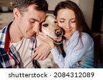 Woman and man hugging their dog labrador retriever breed