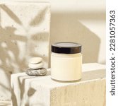 Small photo of Glass jar for cosmetics on concrete podium. Mockup for natural cosmetics. Nature composition with beauty product in jar. Mockup soy wax candle in natural style. Empty jar with cosmetic product