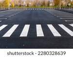 The white and yellow lines of the pedestrian crossing at the intersection of roads in the city. Road safety. Zebra road markings, crossing point of the road, traffic rules