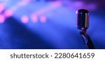 Small photo of Vintage vocal microphone in the dark on a concert stage with pink and blue spot lighting. Live music or podcast wide banner background with copy space