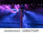 Small photo of Professional vintage microphone on a concert stage before the performance with blue and pink lightning. Retro style vocal mic in the spotlights for festival, jazz club or podcast background