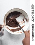 Small photo of Thick chocolate madeleine batter that has rested in a white bowl, thick chocolate cake batter, brownie batter on a silicone spatula