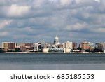Downtown skyline of Madison,the capital city of Wisconsin,USA.Morning view with State Capitol and official buildings in sunlight against beautiful cloudy sky and lake water as seen across lake Monona.