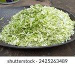 Small photo of Chopped green cabbage in on a brown ppt background,Finely chopped cabbage vegetable in a plastic container,Very finely chopped small and long cabbage green vegetable in a plastic pot,Fresh cabbage veg