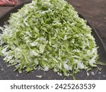 Small photo of Chopped green cabbage in on a brown ppt background,Finely chopped cabbage vegetable in a plastic container,Very finely chopped small and long cabbage green vegetable in a plastic pot,Fresh cabbage veg