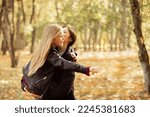 Small photo of Portrait of beauteous family of young woman, teenage girl standing on yellow fallen leaves in forest park in autumn. Mother holding daughter in arms, child stretching hand. Relationship, childhood.