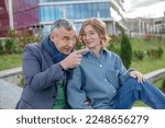 Small photo of Smiling mature man explaining and showing something to young woman, sit on railing against university building. Father and daughter, university entrance, enrollee, university entrant, parent support