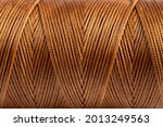 A coil of brown thread. Spool of colored threads on a white background. Waxed sewing thread for leather crafts.