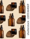 Small photo of Mockup of amber glass bottles and cans are arranged in chaotic manner on beige background with hard shadow on surface. Unmarked packaging for cosmetics close-up. Top view, flat lay. Vertical image