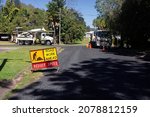 Small photo of Walkerston, Queensland, Australia - 22 July 2021;Electricity power workers or linesmen replacing a damaged electrical supply pole in a suburban street in North Queensland with a yellow road work sign.