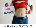 Small photo of Closeup man with his big belly holds paper sign with word " STOP ! Bullying " Concept, campaign for anti bullying, body shaming or parody of others physical appearance.