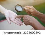 Small photo of Closeup hand holds magnifying glass to inspect palm lines. Concept , palmistry, astrology. Foretelling, mystery, magic, fortune, fate. Prediction for future life , events. Palmist predicting.