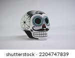 Beautiful and colorful Mexican skull isolated, made of ceramic, and painted by hand. Craft made in Mexico. Turquoise background. Traditional mexican skull for the Day of the Deads.