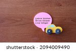 Small photo of Drive safe quotes concept. Top view of toy car and quotes Leave sooner, Drive slower, Live longer.