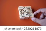 Small photo of Hand arrange wooden cube with house and family icon. Settle down, family planning and home ownership concept