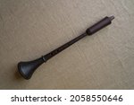Small photo of Antique folk European woodwind reed musical instrument shawm (schalmei, schalmeien) is positioned diagonally of the frame on a gray linen art canvas