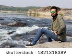 Young Smart Indian Man sitting at River Side, looking at the camera