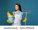 woman in cleaner apron holding bucket of detergents and broom