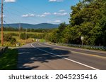 A two lane road going downhill in Sharpsburg, Maryland, USA on sunny summer day