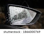 Car side view mirror covered in rain drops