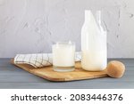 Small photo of Vintage jar with cork of homemade yogurt, kefir, fermented milk or sour cream next to drinking glass and wooden spoon on kitchen table