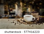 Hot Coffee cup and coffee beans roating on the wooden table and the coffee shop background with copy space