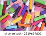 Small photo of Set of multicolor disposable electronic cigarettes on a pink background. The concept of modern smoking, vaping and nicotine.