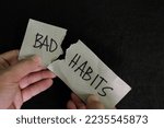 Small photo of Breaking bad habits concept. Human hand tear a paper with word bad habit in dark black background.