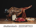Small photo of Spanish ham, manchego cheese and chorizo ​​served with bread and a glass of Spanish red wine on a wooden table with a black background