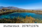 Amazing landscape with a lake and river in the middle of the desert with shades in the water of blue and turquoise green, mountains are distinguished, and the wide desert. Poza Azul, Cuatrociénegas.