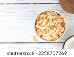 Small photo of Coconut chips or coconut flakes on a white wooden background. Healthy snacks. Coconut dessert. Top view. Copy space.