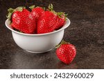 A dramatic, close-up shot of luscious ripe strawberries in a low key setting, emphasizing their rich colors and textures. The moody lighting adds depth and intensity to the image.