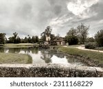 Small photo of Versailles, France - 05.07.2023: a little Marie Antoinette's house and tower by pond