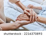 Small photo of Relative holding trembling hand of senior woman with Parkinson's disease lying in hospital bed at medical ward. Diagnosis and treatment of Parkinson's disease and dementia