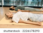 Shavasana. Man with woman wearing in sportswear practice yoga while lying down in savasana or corpse pose at wellness center