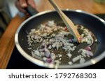Close up of sauteed onion and garlic in the frying pan. Man preparing dinner. Cooking at home concept. Selective focus. Horizontal shot