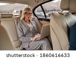 Working Anywhere. Attractive focused businesswoman in stylish classic wear working on laptop while sitting in the car. Business concept. Work concept. Success