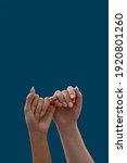 Small photo of Close up of two hands hooking each other little finger pinkie as a symbol of promise or pardon isolated on blue background. People, relationship concept. Vertical shot