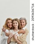 Small photo of Caucasian family of grandmother, mother and granddaughter hugging and looking at camera. Age and generation concept. Family relationship and closeness. White background. Studio shoot. Copy space