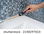 Small photo of dirty grouts in the bathroom and moldy tiles. master cleans dirt with a tool.